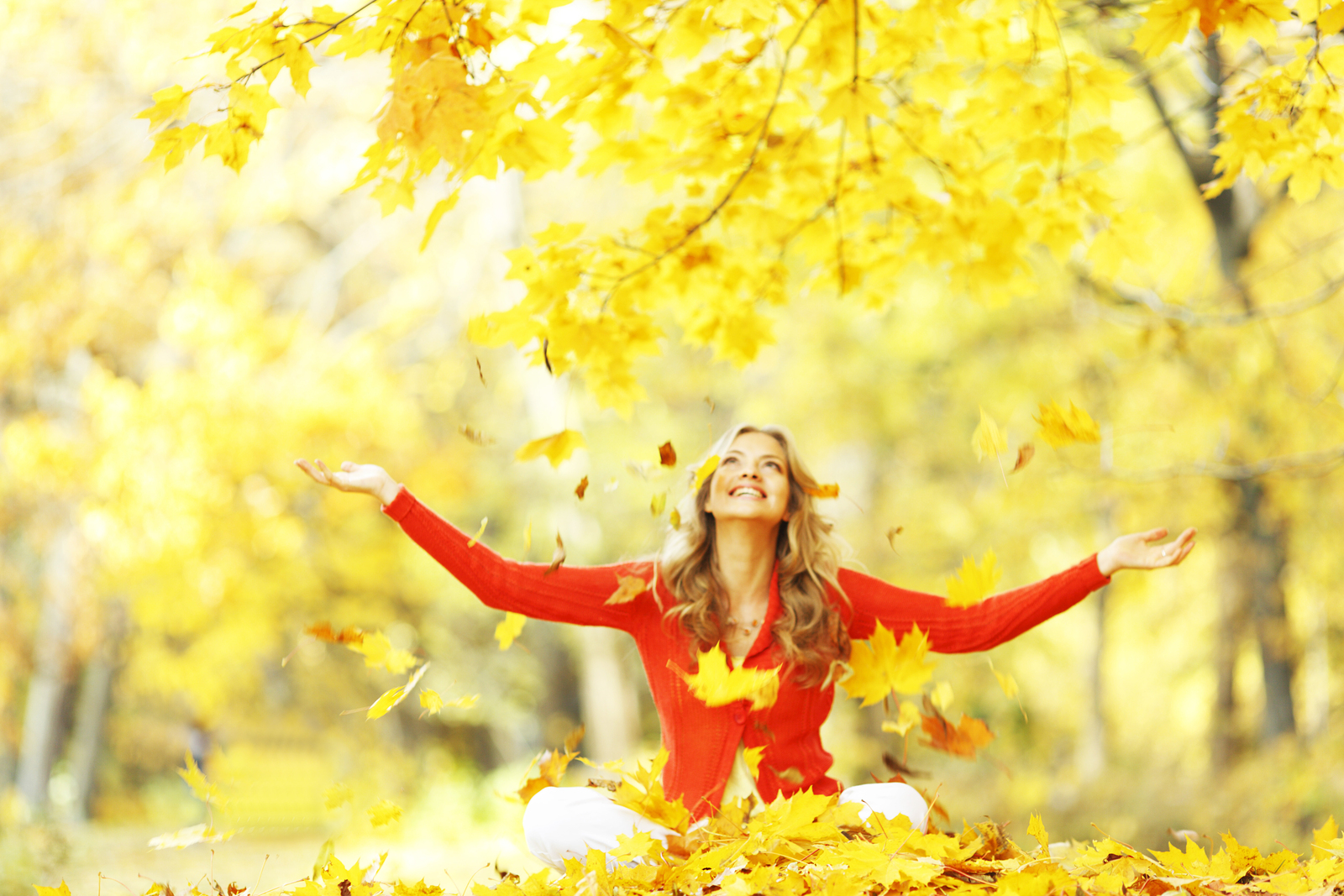 Happy woman in autumn park drop up leaves